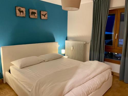 a bedroom with a white bed with a blue wall at Desiree Apartment in Folgarida