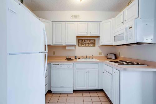 a kitchen with white cabinets and a white refrigerator at Marylander Condominiums, 90 steps from the beach in Ocean City