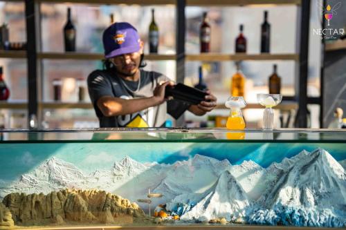a man standing behind a counter with a picture of mountains at Flock Kathmandu in Kathmandu