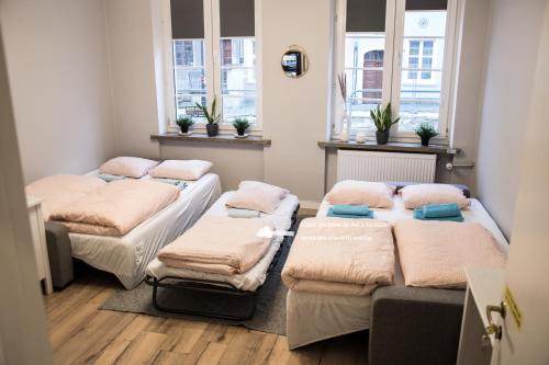 a room with four beds in it with windows at Private rooms in the Old Town in Gdańsk
