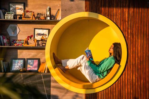 a woman sitting in a circular chair reading a book at Flock Kathmandu in Kathmandu