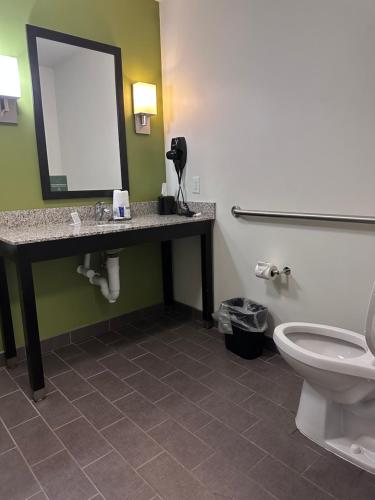 a bathroom with a toilet and a sink and a mirror at Sleep Inn & Suites Gulfport in Gulfport