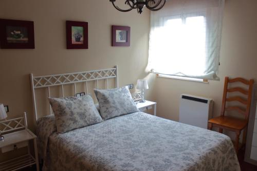 a bedroom with a bed and a window and a chair at Caracas in Lalín