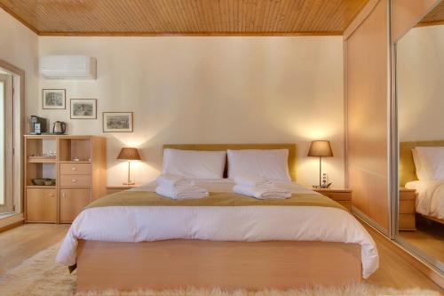 Casa Margarita cozy & peaceful stay in Tzoumerka في يوانينا: غرفة نوم بسرير كبير فيها مصباحين
