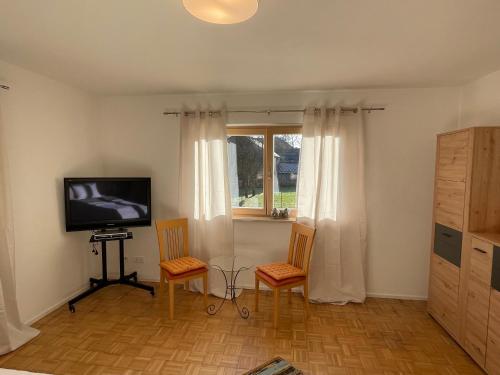een woonkamer met 2 stoelen en een televisie bij Haus Wiesenblick in Thurmansbang