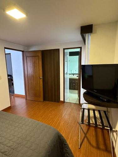 1 dormitorio con 1 cama y TV de pantalla plana en Súper Apartasuite en muy buena ubicación, en Bogotá