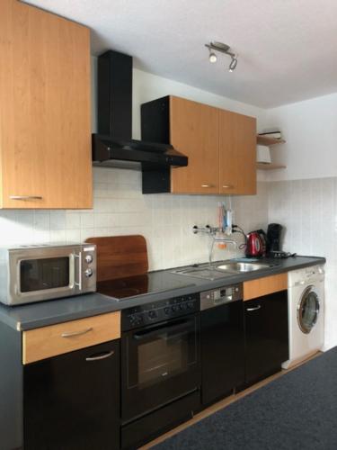 a kitchen with a stove and a microwave at Ferienwohnung Päusken mit Rosengarten im Hochsauerland in Bestwig
