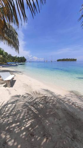 a bench sitting on a beach next to the ocean at Sailboat Anemoi Sailing - Private Charter in San Blas in Mamartupo