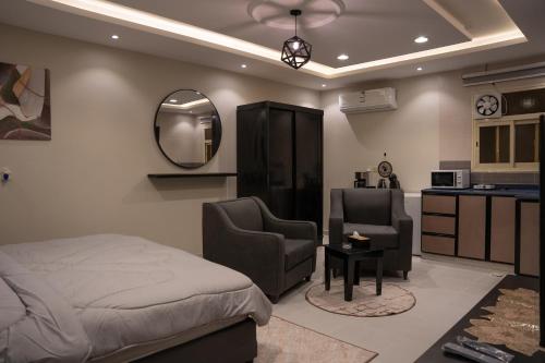 Cet appartement comprend une chambre avec un lit et deux chaises ainsi qu'une cuisine. dans l'établissement Fans Hotel Suites, à Abha