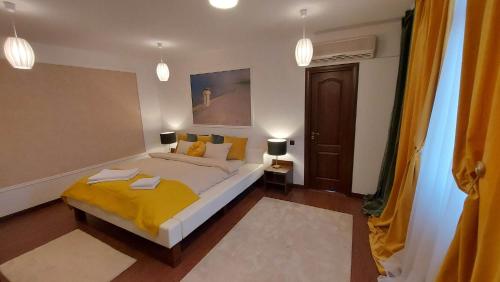 a bedroom with a large bed with a yellow blanket at Ambiennt in Bucharest