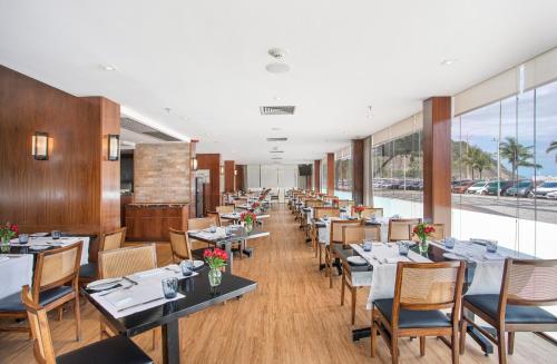 a dining room with tables and chairs and windows at Windsor Leme Hotel in Rio de Janeiro