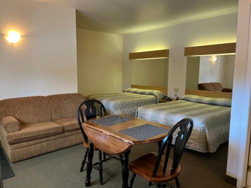 Habitación con 2 camas, sofá y mesa. en Calabogie Motor Inn, en Calabogie
