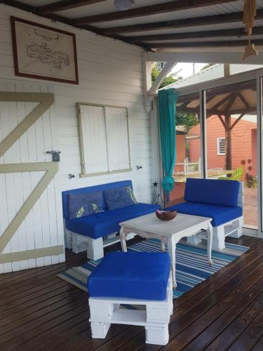 a patio with blue couches and a table on a deck at Bungalow Alizé in Le Robert