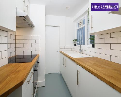 a kitchen with white cabinets and a wooden counter top at 1 Bed Central London Apartment in London