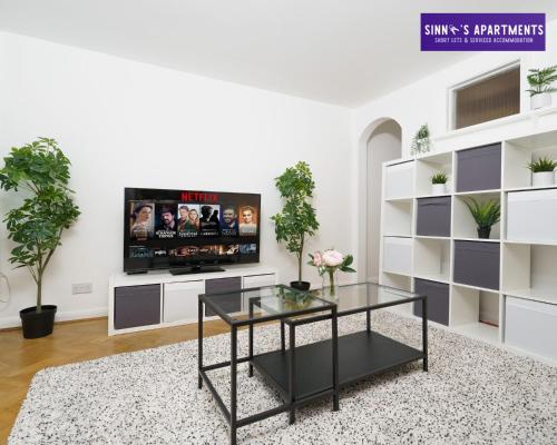 a living room with a tv and a glass table at 1 Bed Central London Apartment in London