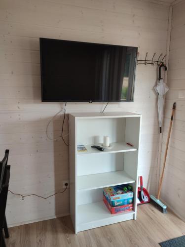 a flat screen tv on top of a white book shelf at Domki u Pana Zielonki in Rusinowo