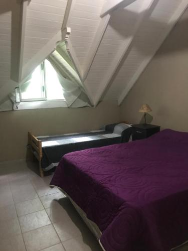 1 dormitorio con cama morada y ventana en Pinamar 497 en Pinamar