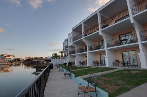 a hotel with tables and chairs next to a body of water at WindWater Hotel and Marina in South Padre Island