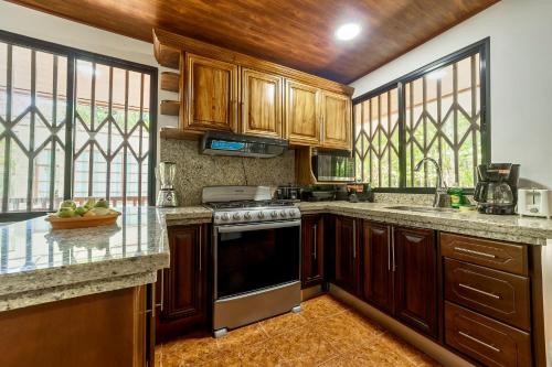 a kitchen with wooden cabinets and a stove top oven at Casa Iris- Home for Family, Steps From the Beach, Pool and Yoga Deck in Puerto Viejo