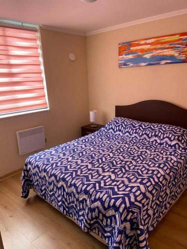 a bedroom with a bed with a blue and white blanket at Departamento Villarrica in Villarrica