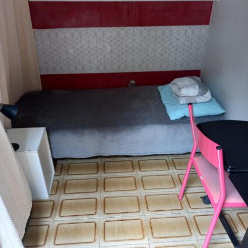 a small room with a bed and a pink chair at Espaço Cápsula in Brasilia
