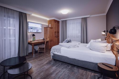 a hotel room with a bed and a desk at Familienresort Ellmauhof - das echte All Inclusive in Saalbach Hinterglemm