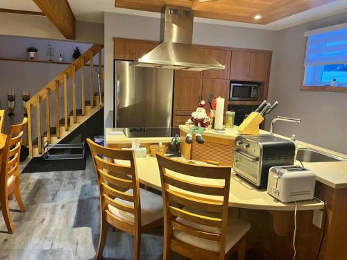 a kitchen with a table with chairs and a microwave at Appartement Mont Édouard, Hébergement paisible à la montagne in LʼAnse-Saint-Jean