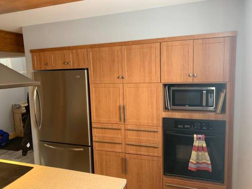 a kitchen with a stainless steel refrigerator and a microwave at Appartement Mont Édouard, Hébergement paisible à la montagne in LʼAnse-Saint-Jean