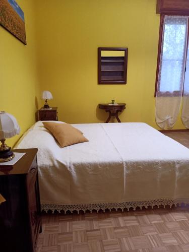 a bedroom with a white bed and a yellow wall at LILY - STORIE DEL BOSCO - in San Felice sul Panaro