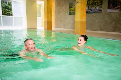 a man and a woman swimming in a swimming pool at Gesundheits- & Wellnessresort Salzerbad in Kleinzell