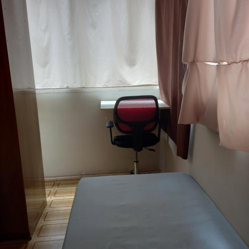 una silla roja en una habitación con ventana en Vaga em quarto em Brasília en Brasilia