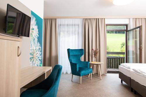a hotel room with a bed and a desk and chairs at Gesundheits- & Wellnessresort Salzerbad in Kleinzell