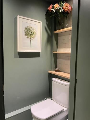 a bathroom with a toilet and flowers on the wall at 3 Bedroom Penthouse Apartment in Manchester