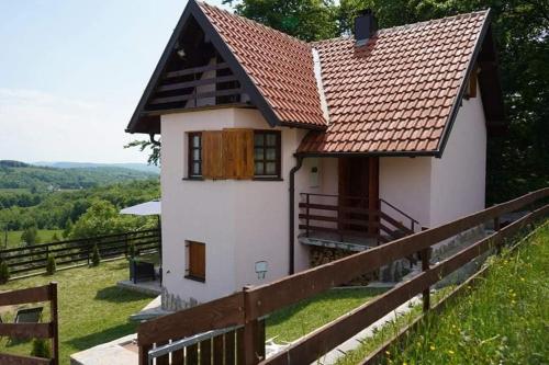 una casa blanca con techo rojo en una colina en Planinska Kuca Tara / Mountain House Tara, en Kaludjerske Bare