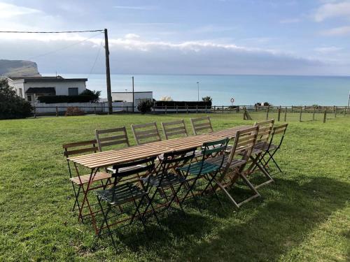 a wooden table and chairs sitting in a field at Grande maison chaleureuse avec vue mer imprenable in Criel-sur-Mer