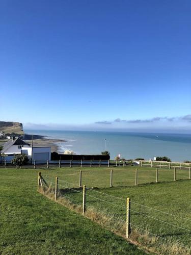 a fence in a field with the ocean in the background at Grande maison chaleureuse avec vue mer imprenable in Criel-sur-Mer