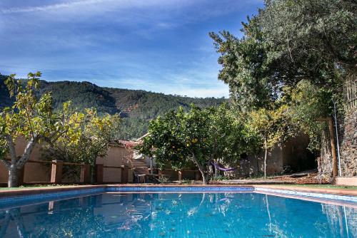 a blue swimming pool with trees and mountains in the background at Caserío de Ovejuela in Ovejuela