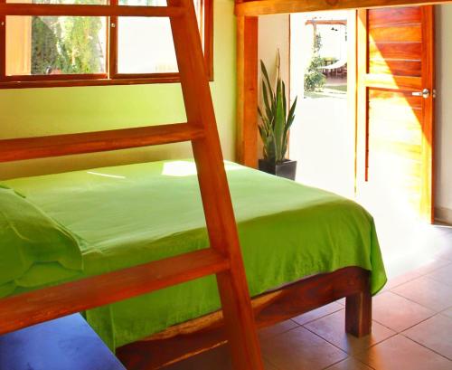 1 dormitorio con litera y colcha verde en BM Zihua Casa de Huéspedes, en Zihuatanejo