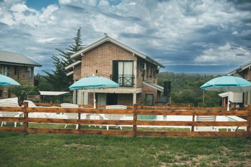 una casa con sillas y sombrillas delante de ella en Pentagrama, casas de campo en Villa General Belgrano