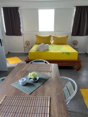 uma sala de estar com uma cama amarela e uma mesa em Bungalow APETAHI em Faaa