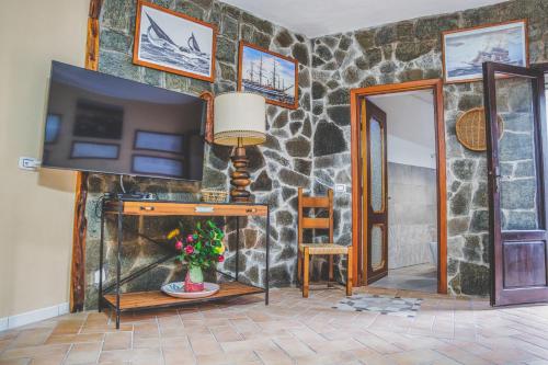 ein Wohnzimmer mit einem TV und einer Steinmauer in der Unterkunft Villa La Caletta in Carloforte