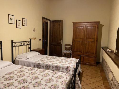 a bedroom with two beds and a wooden cabinet at Agriturismo Relais Villa Passerini in Grosseto