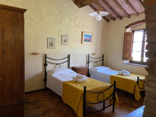 a room with two beds and two tables and a window at Agriturismo Relais Villa Passerini in Grosseto