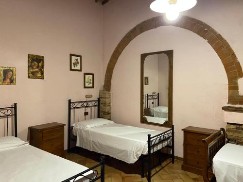 a bedroom with two beds and a mirror in it at Agriturismo Relais Villa Passerini in Grosseto