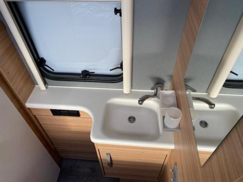 een badkamer met een wastafel en een raam in een kamer bij Wohnwagenvermietung Sylt in Rantum