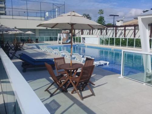 una mesa con sombrilla junto a la piscina en Velutti Home Club - Conforto Lazer e Vista Pro Mar, en Penha