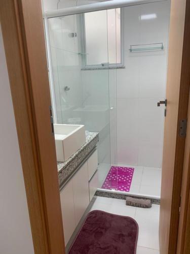 a bathroom with a shower and a pink rug at Apartamento Prainha Arraial in Arraial do Cabo