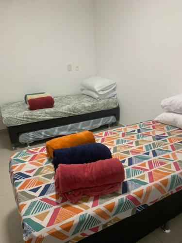 a bed with colorful pillows on it in a room at Apartamento Prainha Arraial in Arraial do Cabo
