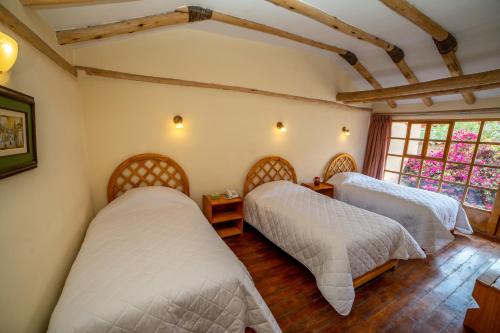 1 dormitorio con 2 camas y ventana en IORANA, en Urubamba