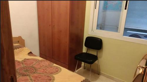 1 dormitorio con silla, cama y ventana en Economic private room in center of Granada, en Granada
